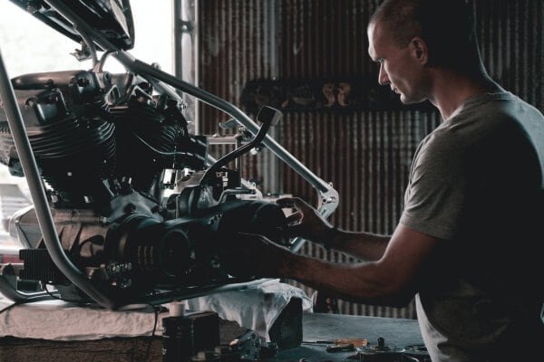 A man providing motorcycle engine repair services in a garage.