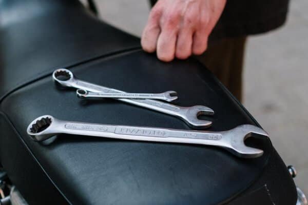 Two wrenches resting on the seat of a motorcycle awaiting services.