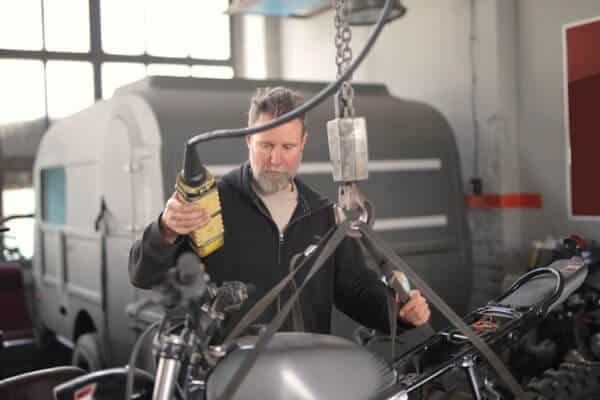 A man is servicing a motorcycle in a garage.