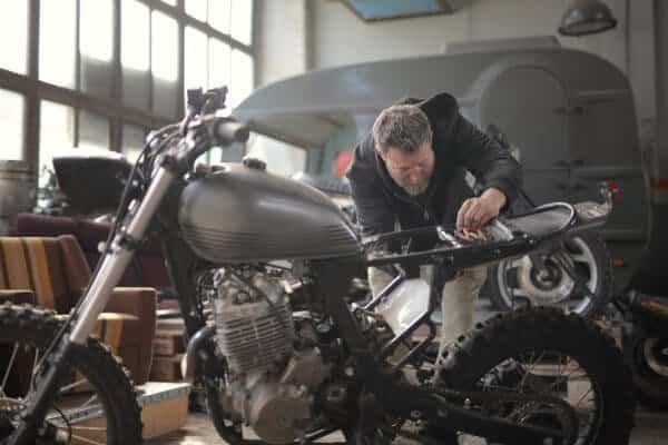 A man is providing services for a motorcycle in a garage.