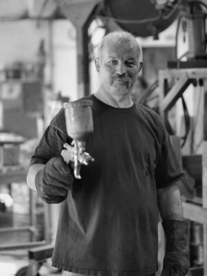 A black and white photo of a man in a factory, away from home.