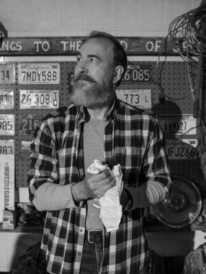 A man with a beard standing in his home garage.