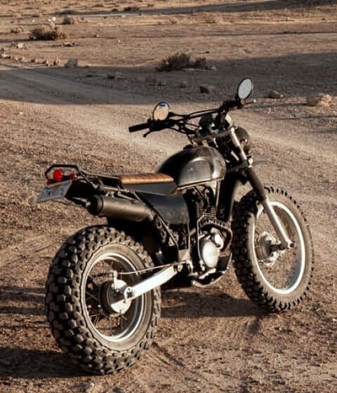 A black dirt bike parked in its home, the desert.