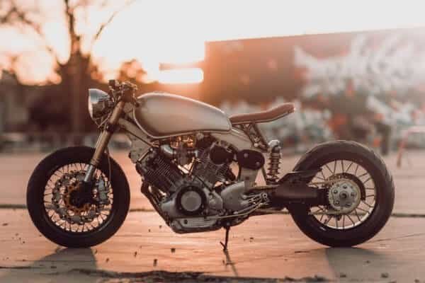 A motorcycle parked in front of a building as the sun sets.